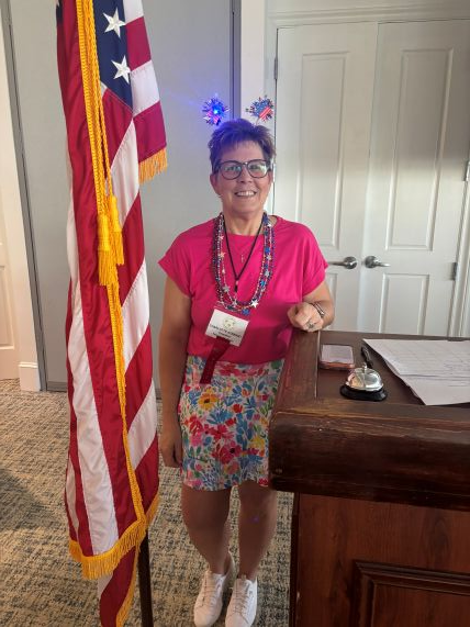 Charlotte Stewart standing beside the American flag at a Gateway Women’s Club meeting