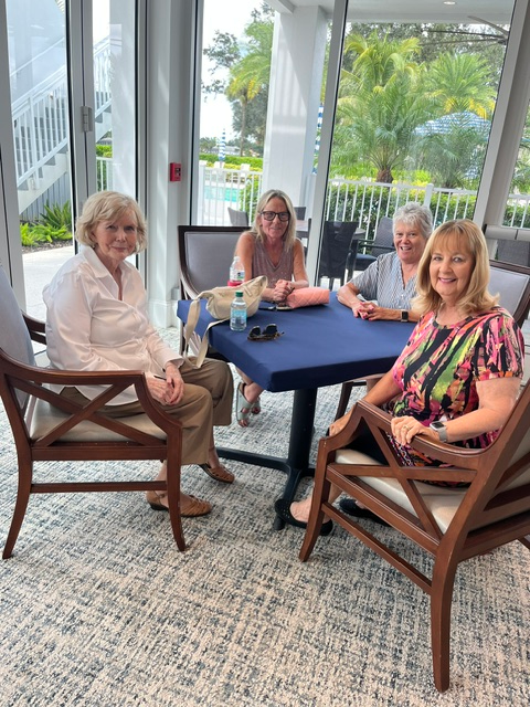 Four Gateway Women’s Club members at a Rummikub table by the windows
