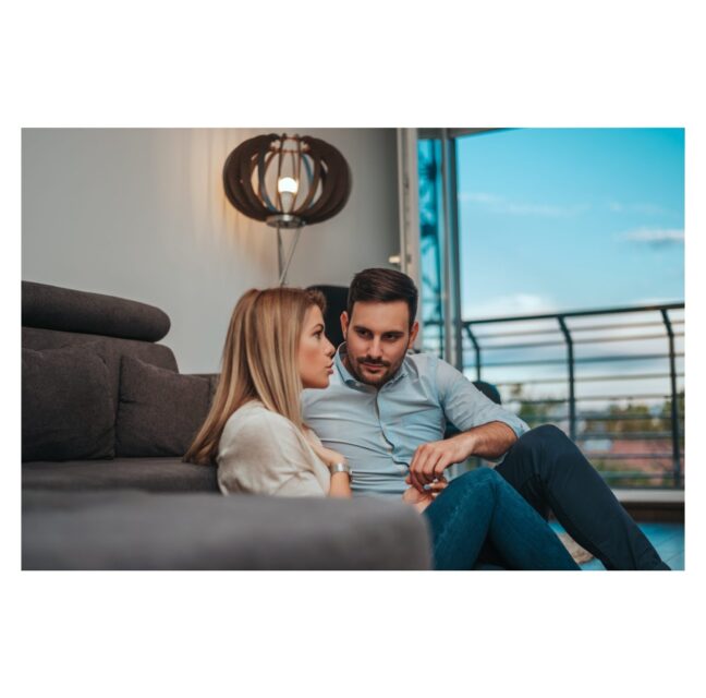 A couple sitting close together on a couch in conversation